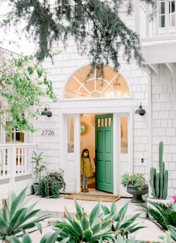 green front door with trees and a girl